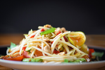 Papaya salad served on plate with dark background, Close up of green papaya salad spicy on the...