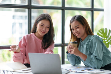 Two young Asian business women discuss work and jointly plan sales and marketing strategy to the...
