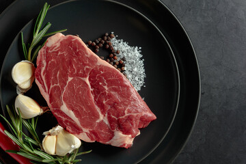 Raw beef meat steak with rosemary, garlic, salt, and pepper.