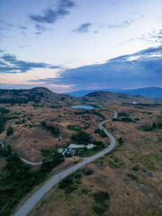 Aerial View of a Scenic Road in the Desert during colorful cloudy sunrise. Near Vernon, Okanagan, British Columbia, Canada.