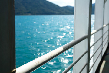 Corridor walkway and railing part of the passenger boat with blurred background of ocean and island...
