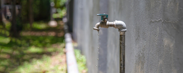 Old faucet outside the house dripping