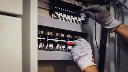 An electrical engineer is inspecting the operation of an electrical control cabinet. maintenance...