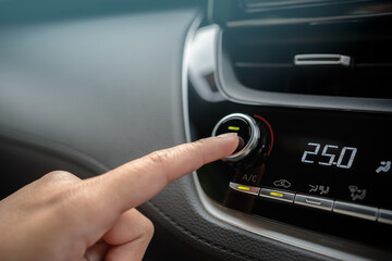 Driver adjusting car air conditioner system at interior panel