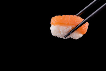 sushi with chopsticks on black background