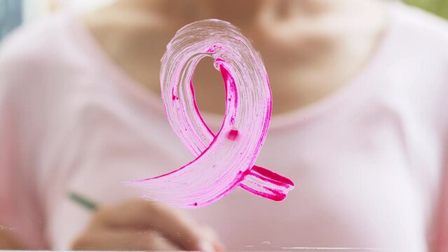 Woman draw pink ribbon sign on mirror, sign of October Breast Cancer Awareness month