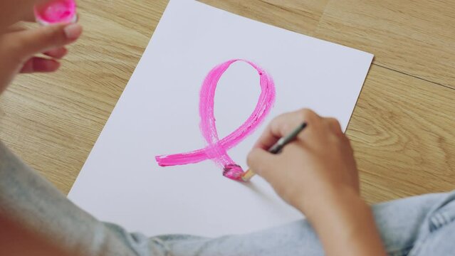 Woman draw ribbon picture on paper by pink color, sign of October Breast Cancer Awareness month