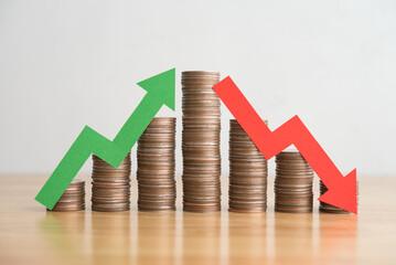 Stack coins and arrow red green graph chart volatility up and down on wooden table background....