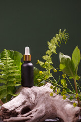 Blank amber glass essential oil bottle with pipette on green background with tropical leaves and...