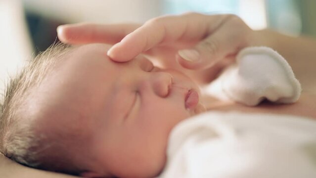 newborn baby close-up portrait lies mother's hand caressing the baby