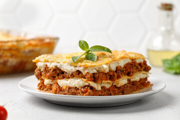 Lasagna. Homemade Italian Lasagne with bolognese meat sauce, cheese and basil on white plate.