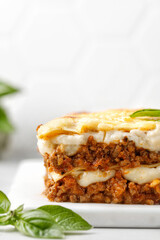 Lasagna. Homemade Italian Lasagne with bolognese meat sauce, bechamel, cheese and basil on white board.