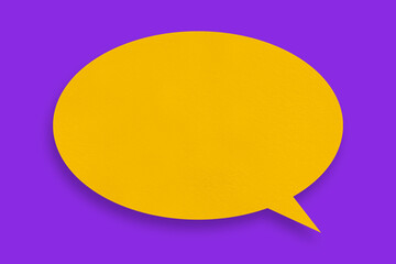 Speech balloon shaped yellow paper against purple background.