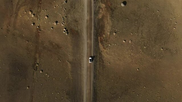 aerial top down view drone of 4x4 car driving on gravel trail path,tracking shot of white offroad vehicle on iceland highland desert road,bird's eye perspective travel concept,icelandic landascape