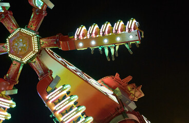 People sitting in a fairground attraction at night.
