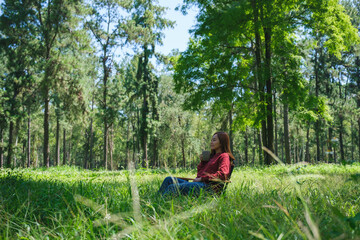 Portrait image of a beautiful young asian woman drinking coffee while sitting on a chair in the park