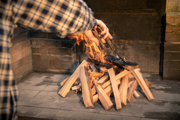 Man preparing a barbeque grill with a burning wood pyre. Male cooking meat and vegetables on fire...