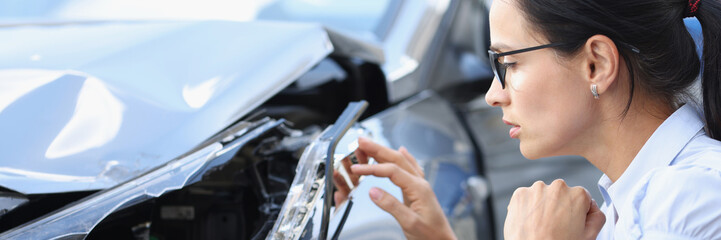 Woman driver looks at broken car after accident