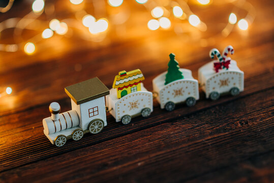 Close up of train toy decoration with with Christmas tree garland lights flickering in background. shallow depth of field. xmas gift card concept.