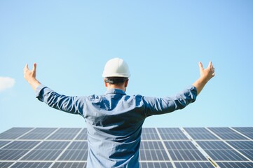 Happy working solar station raising his hands on a background of photovoltaic panels. Science solar energy