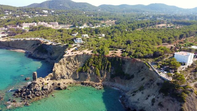 Bays with turquoise green clear water.
Spectacular aerial view flight panorama curved flight drone footage of Aigües Blanques beach Ibiza summer day july 2022. P. Marnitz 4k Cinematic view from above