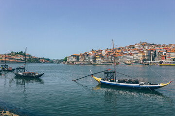 Fototapeta na wymiar Old wooden boats over the calm river and the city behind in Porto 