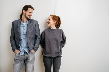 Young people stand in front of a white wall and look at each other