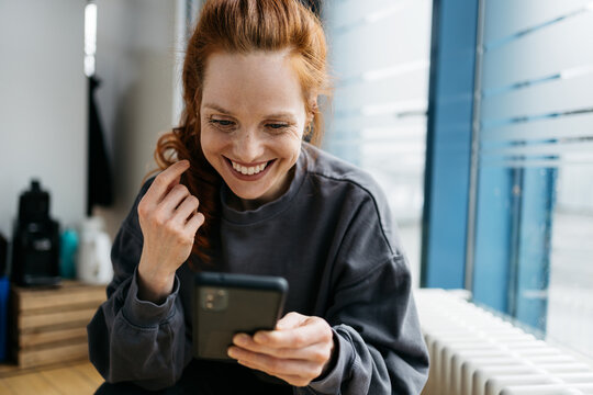 young redhead woman with cell phone takes break in office