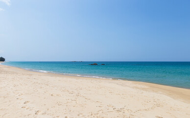 Fototapeta na wymiar Fine sandy beach with blue sea background, tropical summer beach, tropical island in south of Thailand