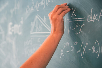 Teacher or student writing on blackboard during math lesson in school classroom