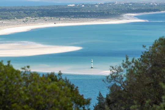 Beautiful landscape of white Gale beach and a lighthouse in the ocean in Troia Peninsula, Portugal.