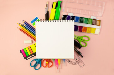 Stationery on a pink background and a notebook on a spring in the center. 