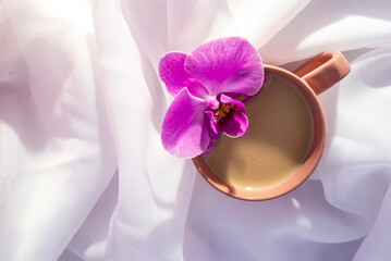 violet orchid flower pink cup of latte coffee with milk white Tulle  wood background, top view...