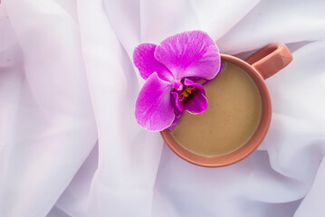violet orchid flower pink cup of latte coffee with milk white Tulle  wood background, top view flatlay morning relax