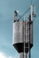 Tall Metal silver water tower ice cream factory Sandriliona blue background Ialoveni Moldova.
