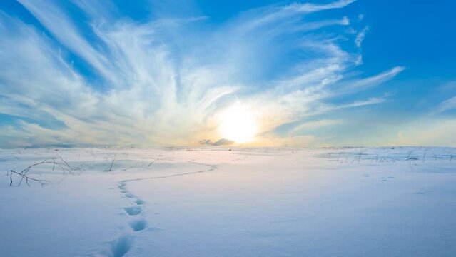winter plain covered by a snow at the sunset with human track, seasonal outdoor time lapse scene