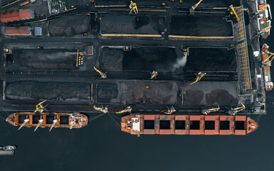 Work of cranes in cargo port, loading black coal on ship for export. Aerial top view