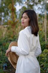 Young farmer asia girl with hat harvesting tomatoes in tropical organic garden