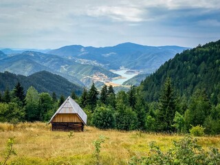 Small wooden house without electricity on a mountain overlooking the lake in the distance. Mountain style architecture. High contrast and saturation