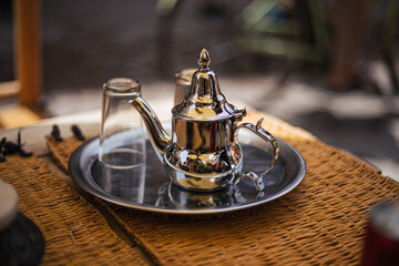 Shining silverware Arabian tea pot served on a plate on a wooden table close up still