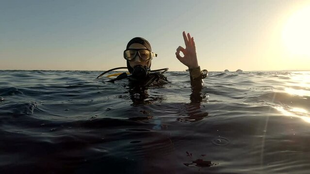 Dver shows OK sign on the sea surface after diving. Red sea, Egypt.