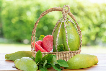 Pomelo fruit in wooden basket on blur garden background, Red Pomelo fruit with slice in wooden...