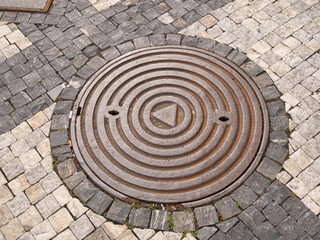 Metal hatch on paving stones.