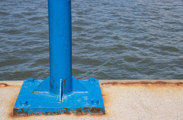 Blue pole at a dock with water in the background and copy space