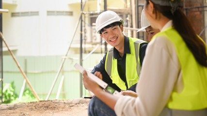 Man engineer supervisor and architect wearing safety helmets discussing the construction process together while visiting a new building