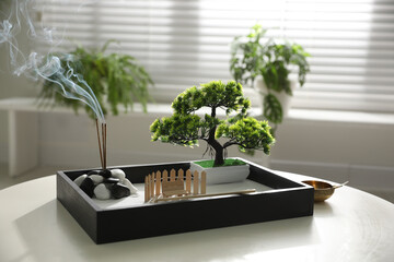 Beautiful miniature zen garden with incense sticks on table indoors