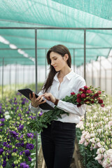 Fresh flowers delivery, women taking order on the tablet. Businesswoman using technologies in her flower business.