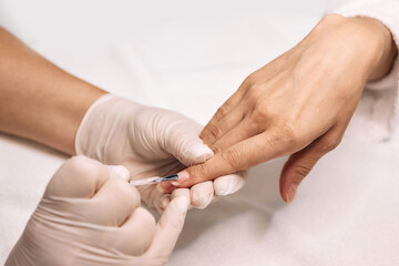 Manicurist covers woman's nails with nail Polish. Woman hand during manicure session with qualified manicurist, nail care process, close-up