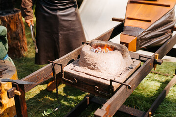 Medieval ancient forge made of stone with bellows outdoors. Festival of Middle Ages Culture and...