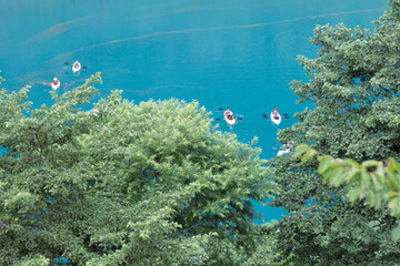 Fototapeta na wymiar エメラルドグリーンの奥四万湖に浮かぶカヌーを楽しむ人々